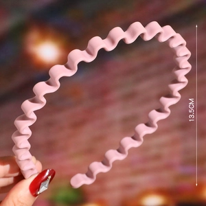 Detail shot of a pink wavy plastic headband showing the 13.5cm size measurement