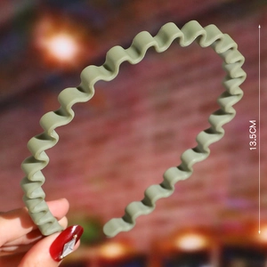 Detail view of 13.5cm green wave shaped woven headband with bead textures