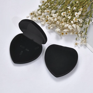 Macro shot of an open black velvet heart-shaped jewelry box with decorative dried flowers