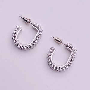 Macro shot of silver U-shaped earrings featuring closely set sparkling square zircons