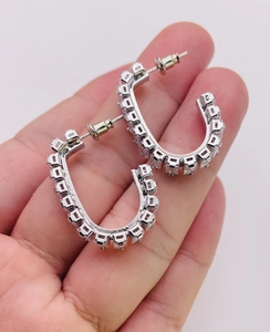Macro shot of silver U-shaped earrings featuring square-cut zircon stones and polished finish