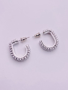 Macro shot of silver U-shaped earrings featuring micro-pave square zircon stones