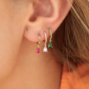 Detail of drop-shaped earrings in emerald green, purple, and rose red with gold diamonds