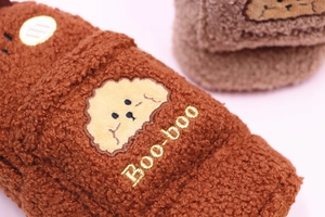 Close-up of caramel plush slipper with teddy fleece texture and cute puppy embroidery