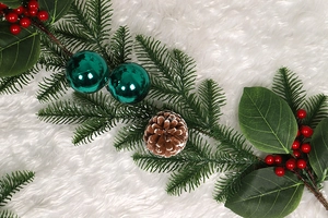 Detail of Christmas garland with peacock green pine needles, red berries and pine cones