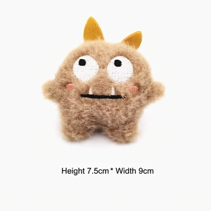Detail view of brown plush monster pin with white teeth and size 7.5cm x 9cm