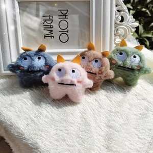 Group of colorful plush monster pins in blue pink and green on a soft white carpet