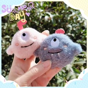 Cute plush monster brooches in pink and blue with detailed embroidery and fluffy texture
