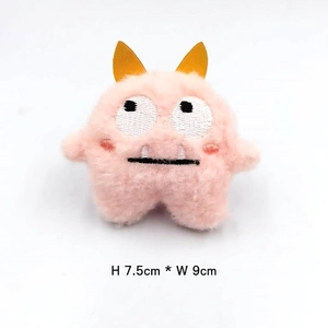 Pink plush monster brooch detail showing 7.5cm height and 9cm width dimensions