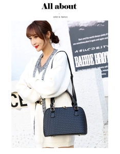 Close-up of black woven leather handbag with gold hardware worn by a fashion model