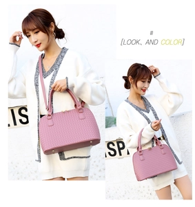 Detail of pink woven texture handbag featuring protective metal feet and elegant top handles