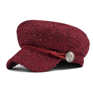 Close-up of burgundy tweed baker boy hat featuring metallic thread and ornate button