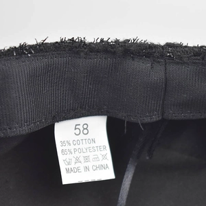 Close-up detail of internal care label on a black newsboy hat showing size 58 and material