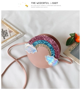 Close-up of pink round crossbody bag with sequined rainbow and iridescent clouds