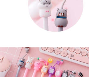 Close-up of cute cartoon animal pens with cat and rabbit silicone charms on pink desk