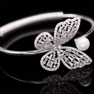 Détail d'un bracelet papillon argenté avec zircons étincelants et une perle blanche chic