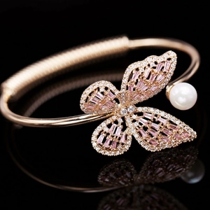 Bracelet manchette papillon or rose avec pierres roses et détail de perle blanche en gros plan