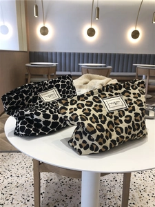 Detail of canvas leopard print makeup bags in black and brown on a cafe table