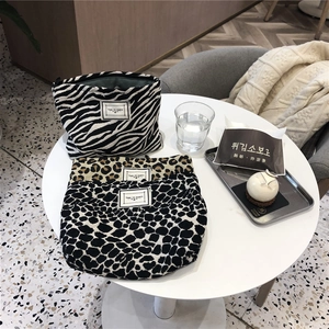 Detail view of zebra and leopard print canvas makeup bags with 'TIME TO PARTY' woven labels