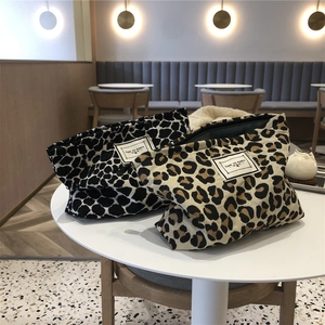 Detail of leopard print canvas makeup bags in brown and black-white on a table