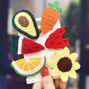 Close-up of handmade knitted fruit hair clips including avocado strawberry and orange