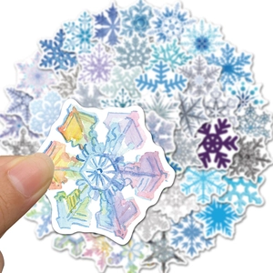 Close-up of hand holding a watercolor snowflake sticker with vibrant blue and purple gradients