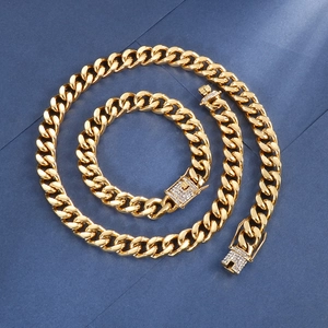 Close-up of golden Cuban link necklace and bracelet set with rhinestone pavé clasp