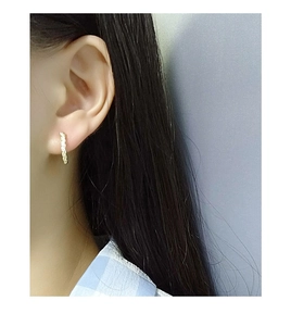 Close-up of golden twist hoop earring with sparkling pavé stones on a female ear