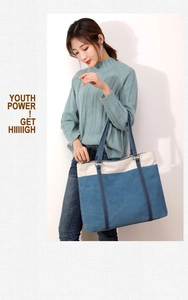 Detail view of large canvas tote bag in denim blue and off-white being held by model