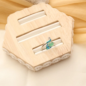 Detail view of silver peacock ring with green gemstone and colorful enamel accents