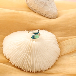 Detailed shot of silver peacock ring with green gemstone and teal enamel detailing