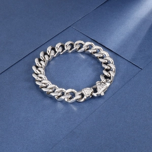 Detailed macro view of silver Cuban link bracelet with vintage engraved buckle closure