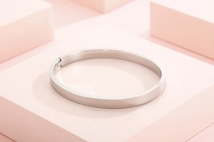Bracelet jon jonc en acier inoxydable argenté sur un socle géométrique rose moderne