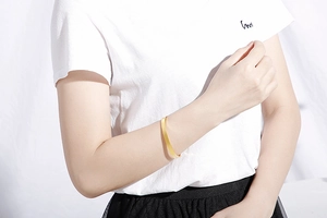 Bracelet jonc en acier inoxydable doré sur le poignet du mannequin sur fond blanc