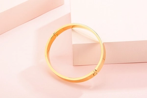 Gros plan d'un bracelet en acier doré avec motif vis sur des blocs géométriques roses