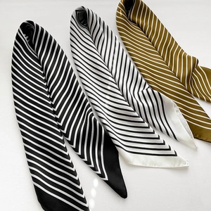 Flat lay of three striped silk scarves in black, white, and gold diagonal patterns