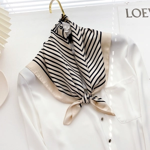 Close-up of a striped silk scarf tied on a white shirt collar for a minimalist look