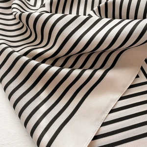Detailed close-up showing the smooth silk texture and black and white stripes of the scarf