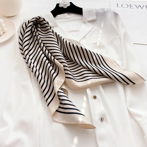 Macro detail of beige silk scarf with classic black stripes and elegant glossy texture
