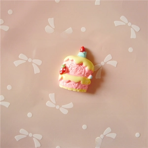 Close-up of pink and yellow resin cake charm with strawberry and candle for DIY crafts
