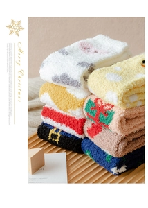 Close-up of soft coral fleece Christmas socks with festive patterns on a wooden tray