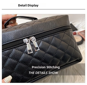 Detail view of precise stitching and gold metal zipper on black quilted PU leather makeup bag