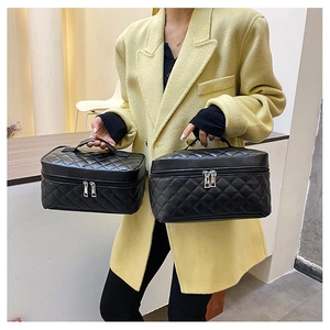 Detail of two black quilted PU leather makeup bags with silver zippers and handles