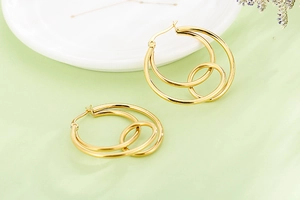 Detailed view of intertwined golden double hoop earrings with polished mirror finish