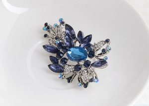 Détails macro d'une broche fleur vintage en argent avec cristal bleu et gemmes violettes