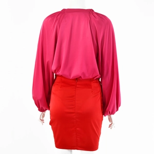 Vista posteriore del top fucsia con maniche a lanterna e minigonna in raso rosso con zip