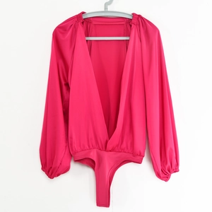 Dettaglio di body in raso plissettato fucsia con scollo a V e maniche a lanterna