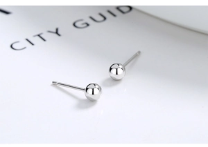 Macro shot of minimalist S999 sterling silver ball earrings with smooth metallic finish