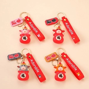 Flat lay of four creative zodiac cow keychains with lucky red pouches and cute wrist straps