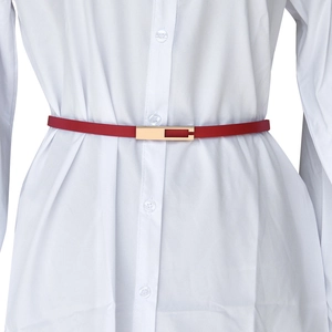 Detail of a thin red leather belt with gold rectangular buckle styled on white shirt